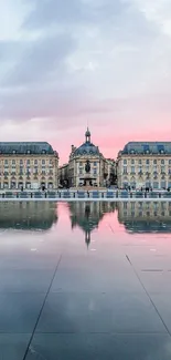 Elegant city architecture reflected on water at sunset with blue sky.