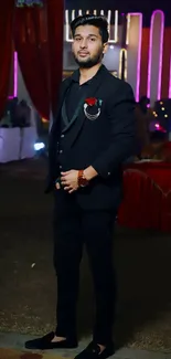 Man in black suit with red accents at an evening event.