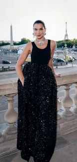 Elegant black evening dress in urban cityscape setting.