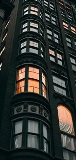 Elevated view of a tall building with glowing windows at dusk.