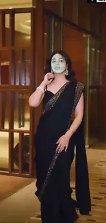 Elegant woman in a black saree posing indoors.