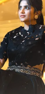 Person in a black ornate dress sitting elegantly on stairs.