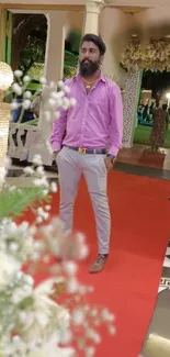 Stylish man at elegant event with red carpet and floral decor.