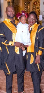 Family dressed in gold and black traditional attire, celebrating together.