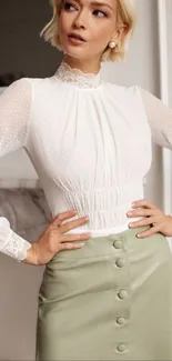 Elegant woman in white lace blouse and green skirt against classic decor.