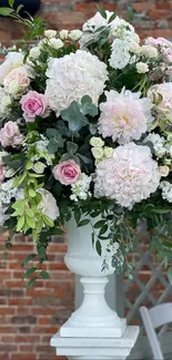 Elegant floral arrangement with pink roses and hydrangeas against a rustic backdrop.