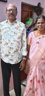 A man and woman in elegant floral attire standing indoors.