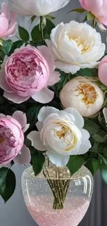 Floral bouquet with pink peonies and white flowers in a clear vase.
