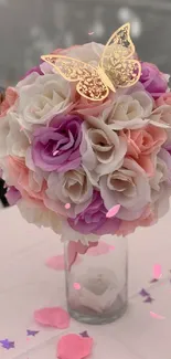 Floral bouquet with pastel roses and gold butterflies on a table.