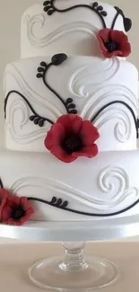 Three-tiered white cake with red flowers and black swirls.