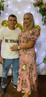 Couple at floral-themed celebration with lights.