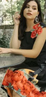 Woman in elegant black floral dress seated in garden.