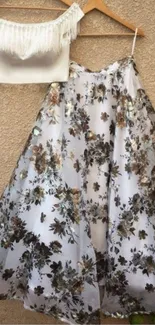 A floral dress hanging against a beige wall.