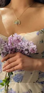 Woman in floral dress holding lilacs.