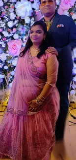 Couple posing in front of floral backdrop at an event.