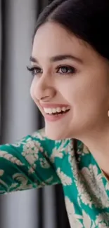 Smiling woman in floral green dress with stylish earrings.