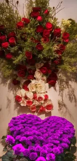 Heart-shaped floral arrangement with red, white, and purple roses on wallpaper.