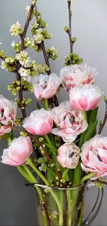 Elegant pink roses in a vase with blooming branches.