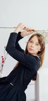 Woman in black dress holding flowers, set against a white background.