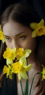 Woman with yellow flowers in hair and hand against dark background.