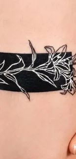 Elegant floral tattoo with black band design on skin.