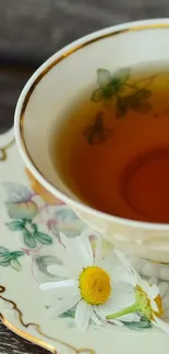 Elegant tea cup with floral design and a daisy in it.