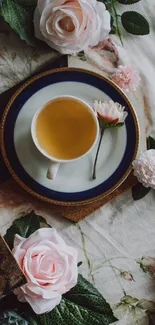 A cup of tea surrounded by pink roses on a floral wallpaper.