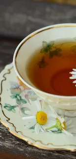 Vintage tea cup with floral design and daisies on a wooden table.