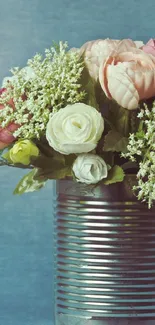 Vintage floral tin can with roses on a blue-gray background.