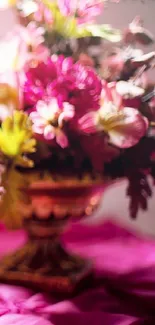 Blurry floral arrangement with vibrant pink and yellow flowers in an ornate vase.