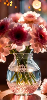 Elegant pink daisy flowers in a glass vase under warm lighting.