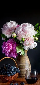 Vase of peonies with grapes and wine against a dark background.