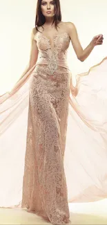 Model in elegant, flowing beige lace gown on light background.