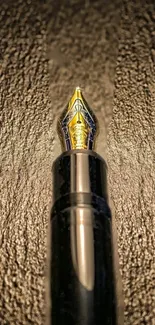 Close-up of a stylish gold nibbed fountain pen against a textured background.