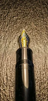 Elegant black fountain pen with golden nib on dark texture.