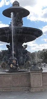 Elegant fountain with sculptures and flowing water under a blue sky.