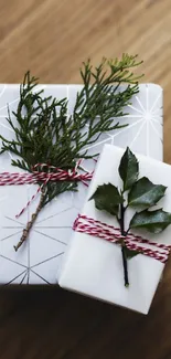 Elegant gift boxes with greenery and twine on a wooden surface.