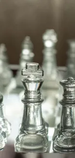 Glass chess pieces on a board with focus on the king and queen.