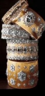 Stack of gold and silver embellished bangles on dark background.