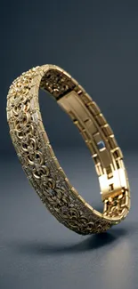 Elegant gold bracelet with intricate design on dark background.