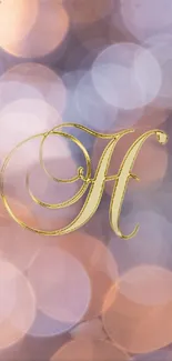 Elegant gold letter H on dreamy bokeh background.