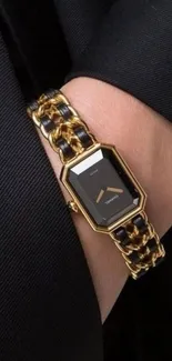 Elegant gold chain watch on wrist, black suit background.