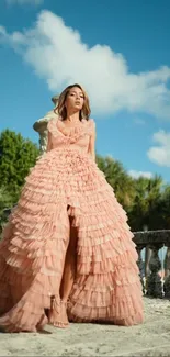 Woman in an elegant peach gown in a scenic outdoor setting.