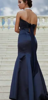 Woman in midnight blue gown on elegant marble staircase.