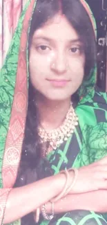 Woman in a green sari with intricate patterns and jewelry.