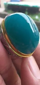 Close-up of a gorgeous green gemstone ring, held delicately.