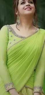 Woman in a vibrant green saree with intricate design standing outdoors.