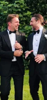 Groomsmen in tuxedos laughing outside.