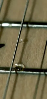 Close-up of guitar strings with a beige wood background for mobile wallpaper.