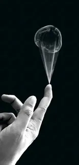 Hand balancing a bubble on black background.